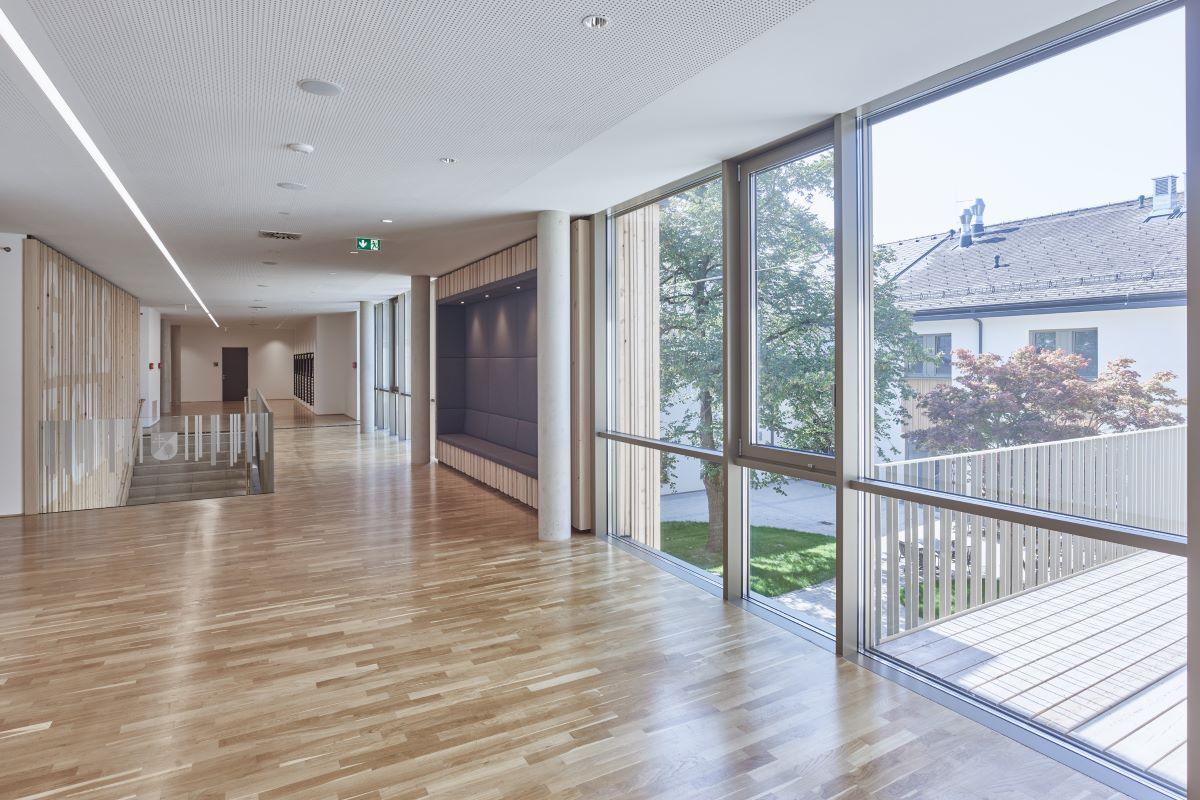 Innenansicht des Gemeindezentrums. Heller Raum, großflächige Fenster mit Holzboden ausgestattet.